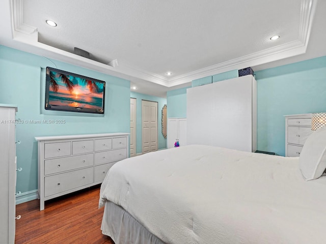 bedroom with dark wood-type flooring, crown molding, and a raised ceiling