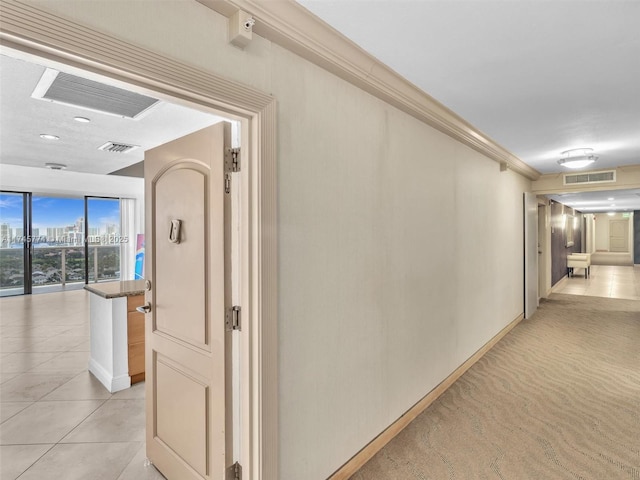 hallway with crown molding and light tile patterned floors