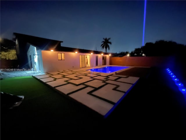 pool at twilight with a fenced in pool and a patio area