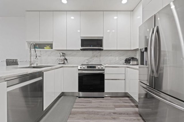 kitchen with sink, appliances with stainless steel finishes, white cabinets, and decorative backsplash