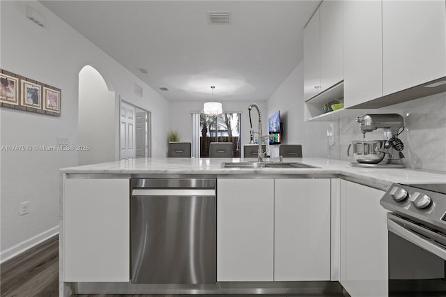 kitchen with stainless steel appliances, pendant lighting, sink, white cabinetry, and kitchen peninsula