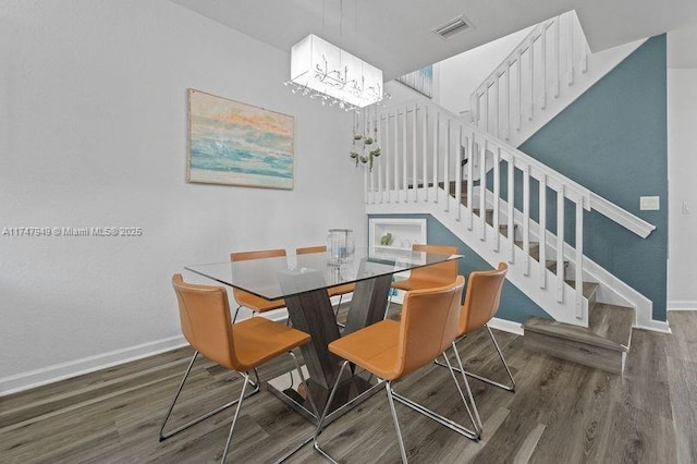 dining room with dark wood-type flooring and an inviting chandelier