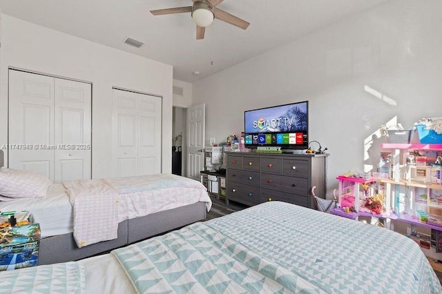 bedroom with ceiling fan, two closets, and hardwood / wood-style floors