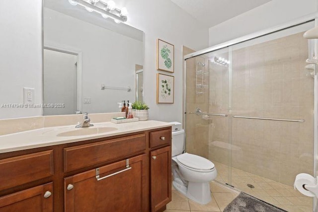 bathroom with tile patterned floors, toilet, vanity, and a shower with shower door