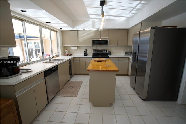 kitchen with a sink, stainless steel appliances, tasteful backsplash, and wood counters