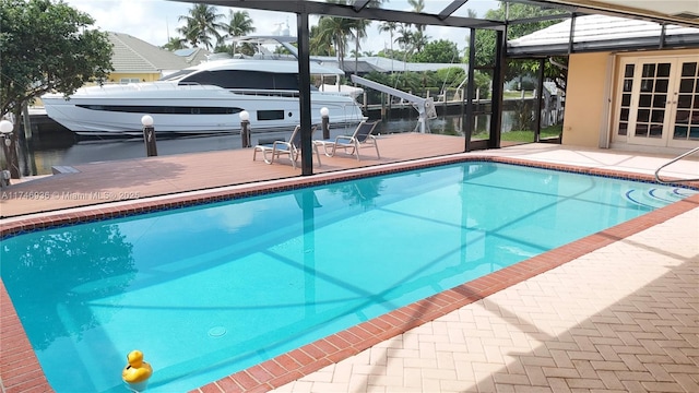 outdoor pool featuring a lanai, a water view, a patio area, and a dock