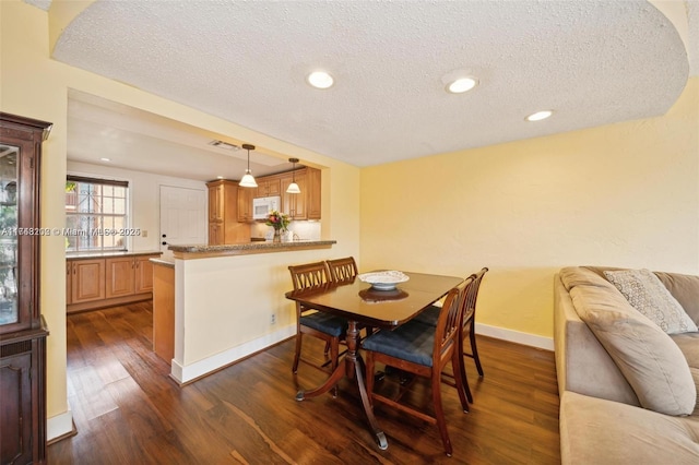 dining area featuring a textured ceiling and dark hardwood / wood-style floors