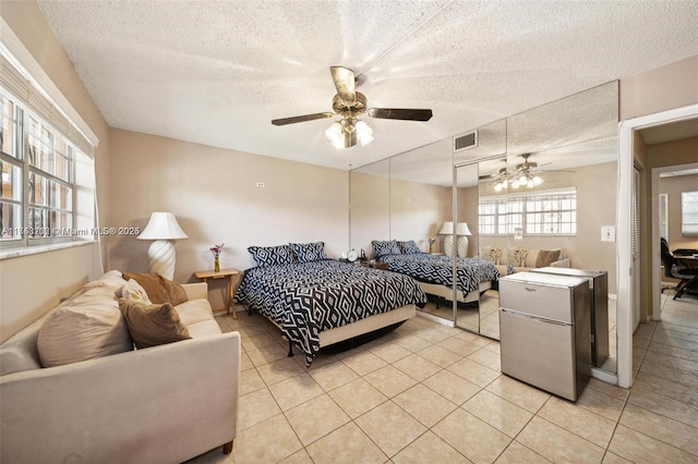 tiled bedroom with a textured ceiling, refrigerator, and ceiling fan