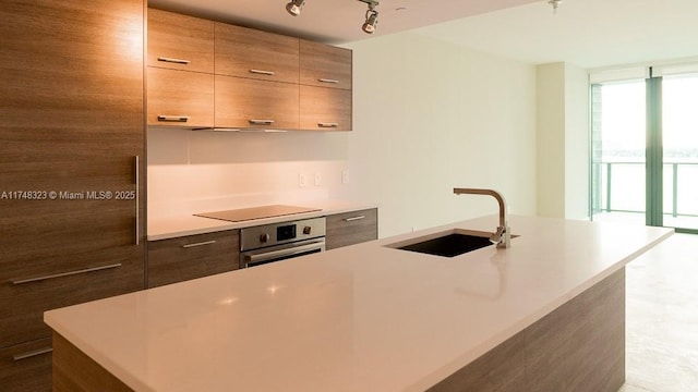 650 NE 32nd St Unit 2105, Miami, FL 33137 - kitchen featuring stainless steel oven, modern cabinets, light countertops, expansive windows, and a center island with sink