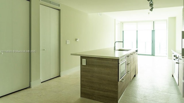 650 NE 32nd St Unit 2105, Miami, FL 33137 - kitchen featuring modern cabinets, light countertops, a kitchen island with sink, and stainless steel microwave