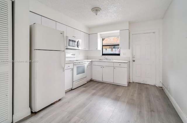 kitchen featuring light countertops, white appliances, white cabinetry, and light wood-style floors