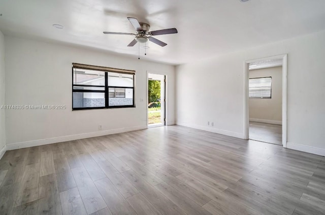 empty room featuring light wood-type flooring, baseboards, and a ceiling fan