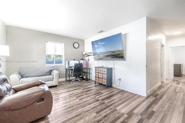 living area with visible vents, baseboards, and wood finished floors