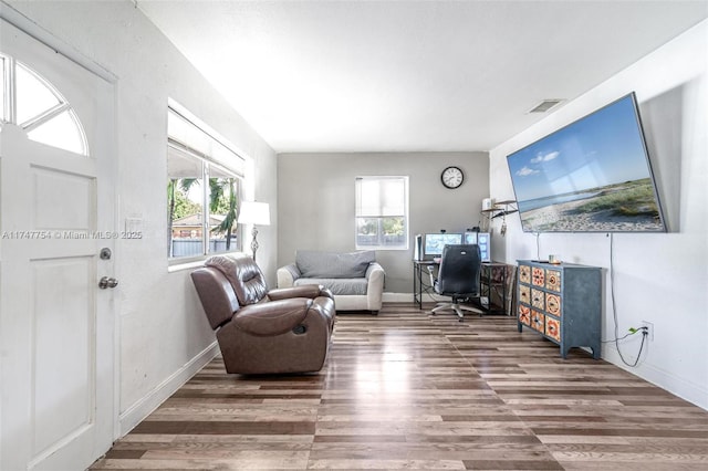 home office with baseboards, wood finished floors, visible vents, and a healthy amount of sunlight