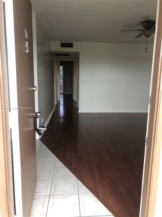 hallway featuring visible vents, baseboards, and wood finished floors