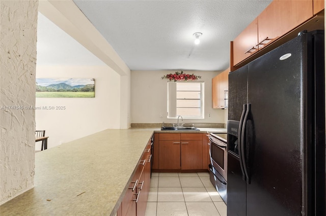 kitchen with kitchen peninsula, electric range, sink, light tile patterned flooring, and black fridge