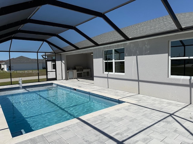 view of pool featuring a patio area, exterior kitchen, a grill, and a lanai