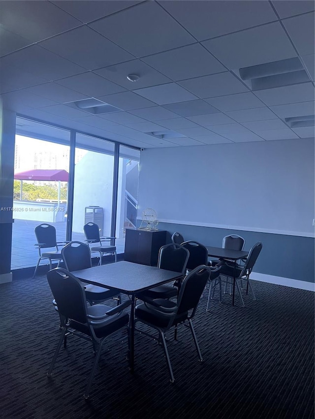 carpeted dining space featuring a paneled ceiling and floor to ceiling windows