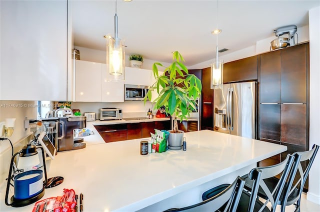 kitchen featuring pendant lighting, white cabinetry, appliances with stainless steel finishes, and kitchen peninsula