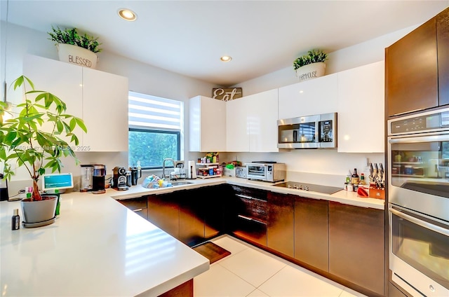 kitchen featuring appliances with stainless steel finishes, light tile patterned flooring, sink, and white cabinetry