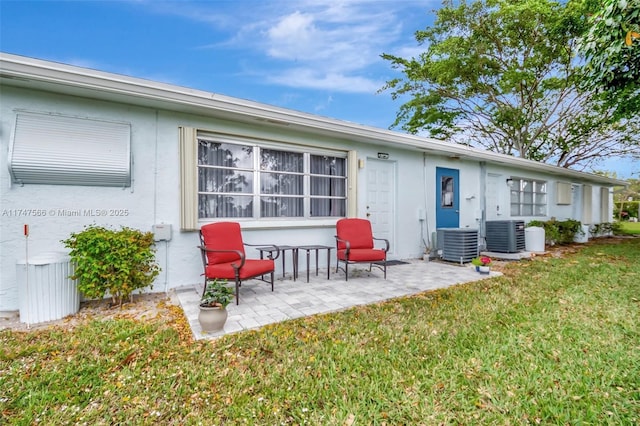 rear view of house with a patio, a lawn, and central AC