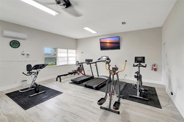 workout area with a wall mounted AC and light hardwood / wood-style floors