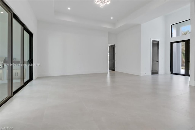 spare room with a high ceiling, a raised ceiling, and french doors