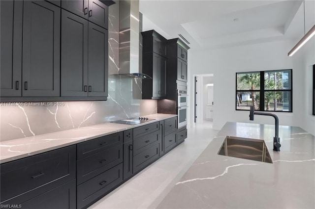 kitchen with sink, backsplash, a tray ceiling, black electric cooktop, and wall chimney exhaust hood