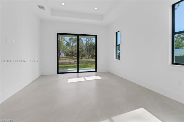 empty room with plenty of natural light and a raised ceiling