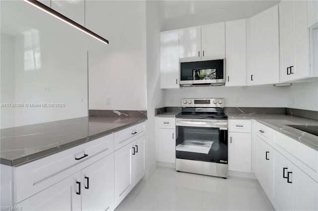 kitchen featuring dark stone countertops, stainless steel appliances, and white cabinets