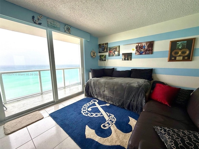 tiled bedroom featuring a textured ceiling, access to exterior, and a water view