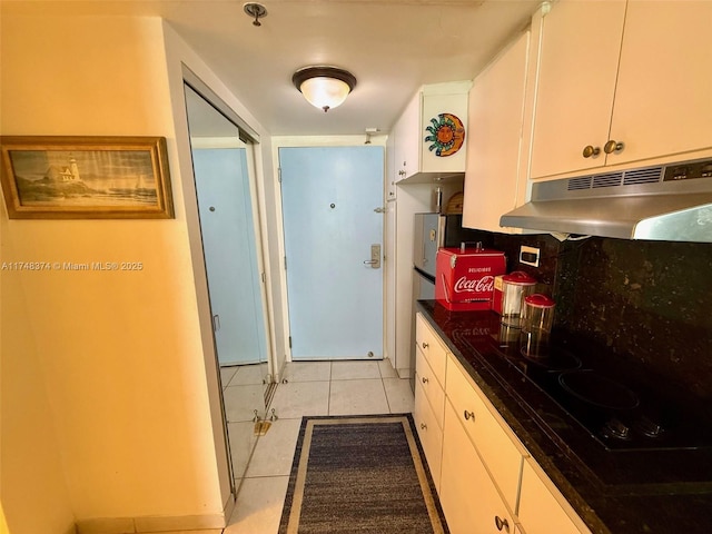 kitchen with light tile patterned floors, black stovetop, white cabinets, and decorative backsplash