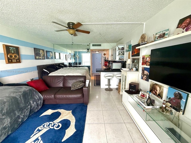 living room with ceiling fan, light tile patterned floors, and a textured ceiling