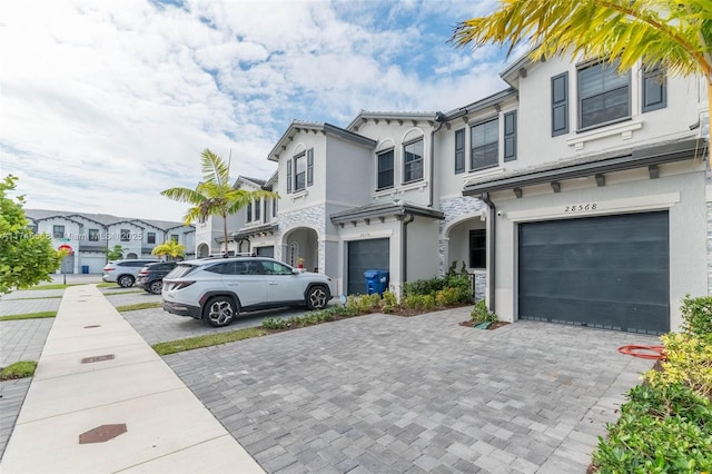 view of front facade featuring a garage, a residential view, decorative driveway, and stucco siding