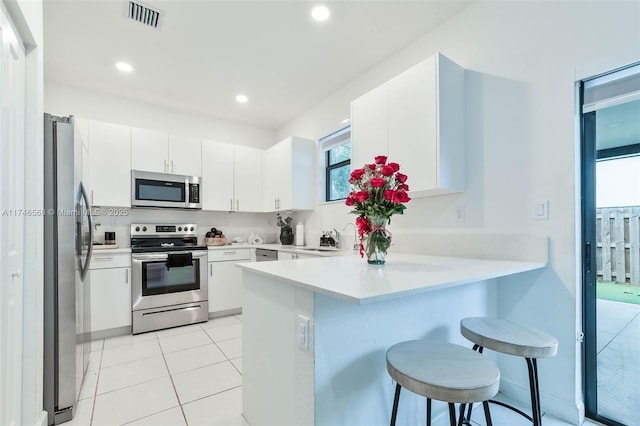 kitchen with visible vents, white cabinetry, stainless steel appliances, and light countertops