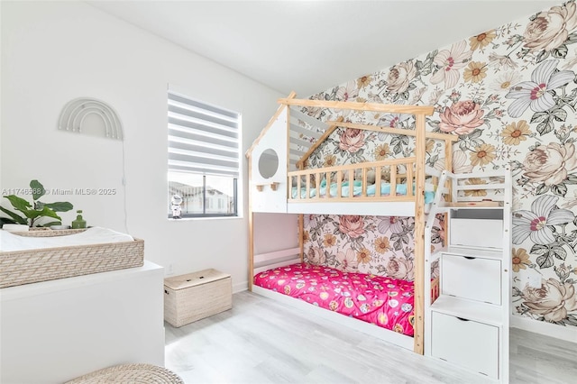 bedroom featuring wallpapered walls, vaulted ceiling, baseboards, and wood finished floors