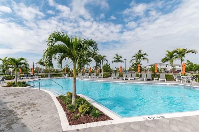 community pool with a patio area and fence