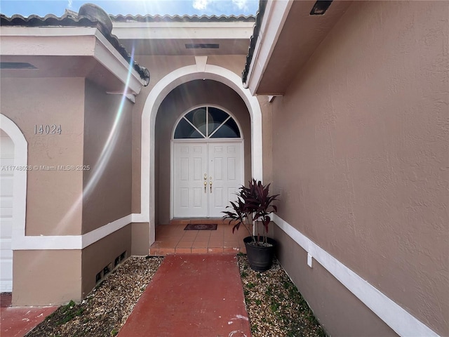 property entrance with a tile roof and stucco siding