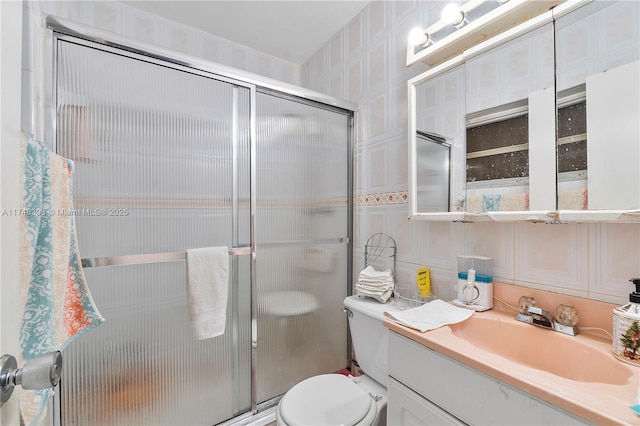 bathroom featuring a shower with shower door, vanity, and toilet