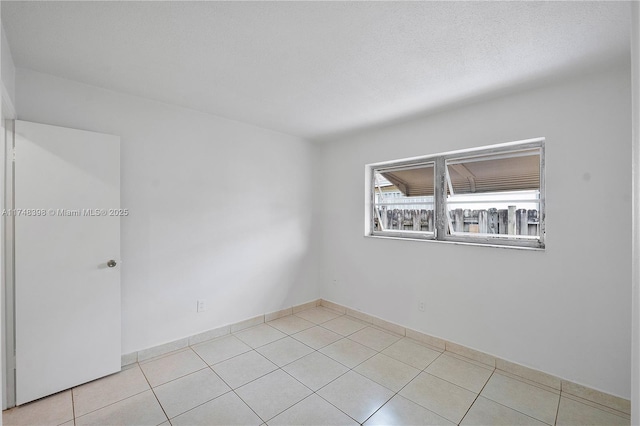 spare room with a textured ceiling and light tile patterned floors