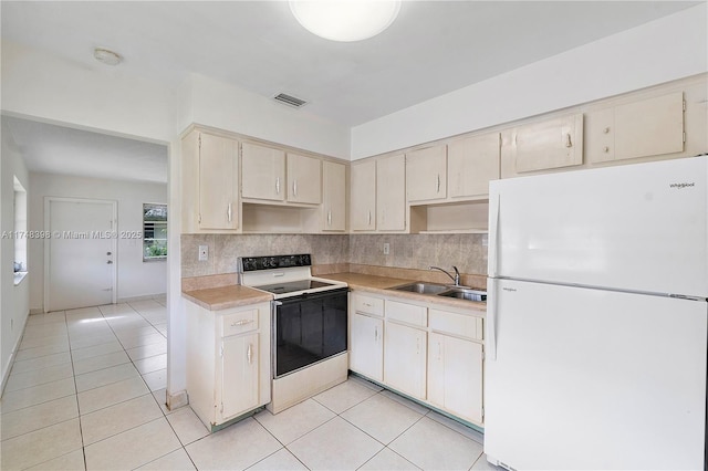 kitchen with electric range oven, backsplash, freestanding refrigerator, light countertops, and a sink
