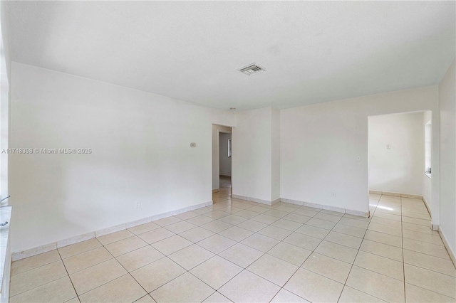 empty room featuring visible vents, baseboards, and light tile patterned floors