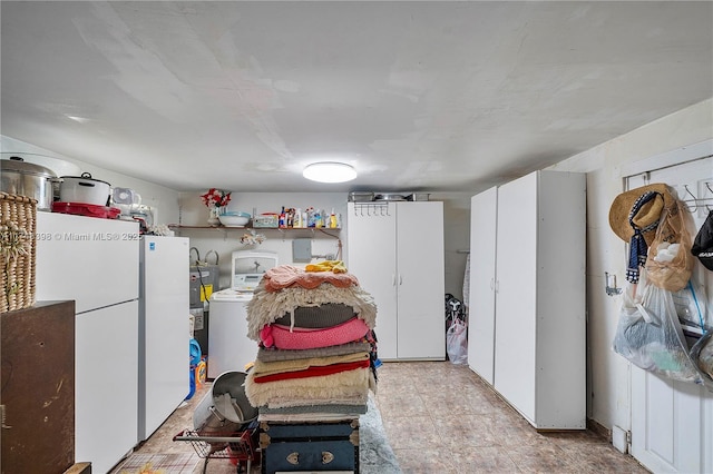 kitchen featuring light countertops, freestanding refrigerator, washer / clothes dryer, and white cabinets