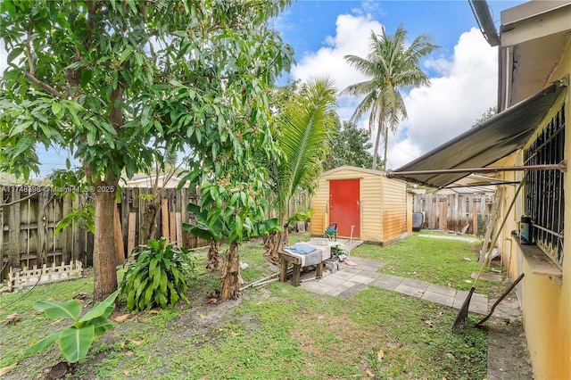 view of yard with a fenced backyard, a storage unit, and an outbuilding