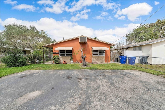 back of property featuring a lawn, driveway, and fence