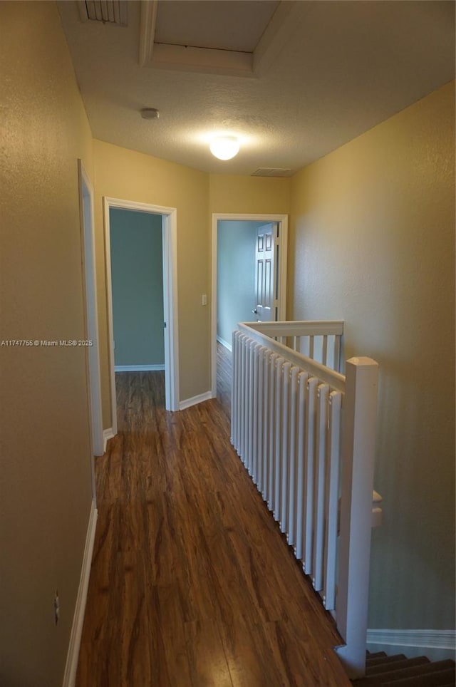 hallway with a textured ceiling and dark wood-type flooring