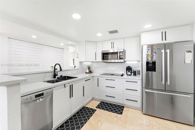 kitchen featuring sink, stainless steel appliances, white cabinetry, and backsplash