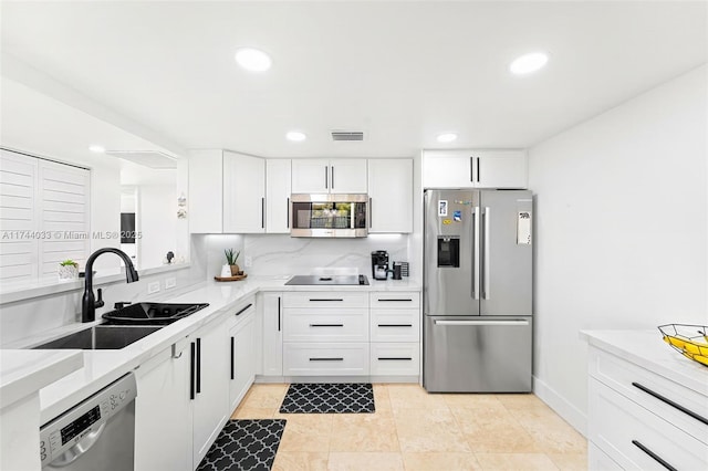 kitchen with appliances with stainless steel finishes, sink, white cabinetry, and backsplash