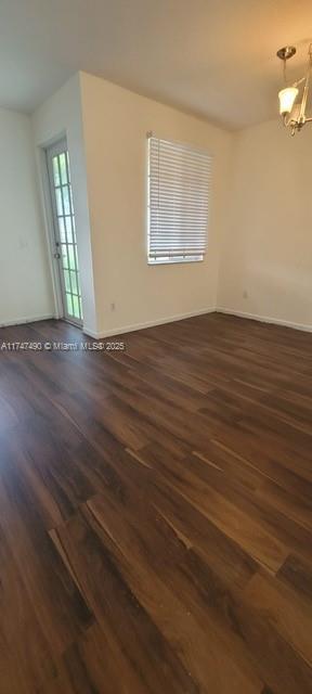 spare room featuring dark hardwood / wood-style flooring and a notable chandelier