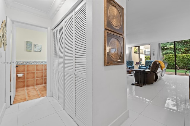 corridor with tile walls, light tile patterned flooring, and crown molding